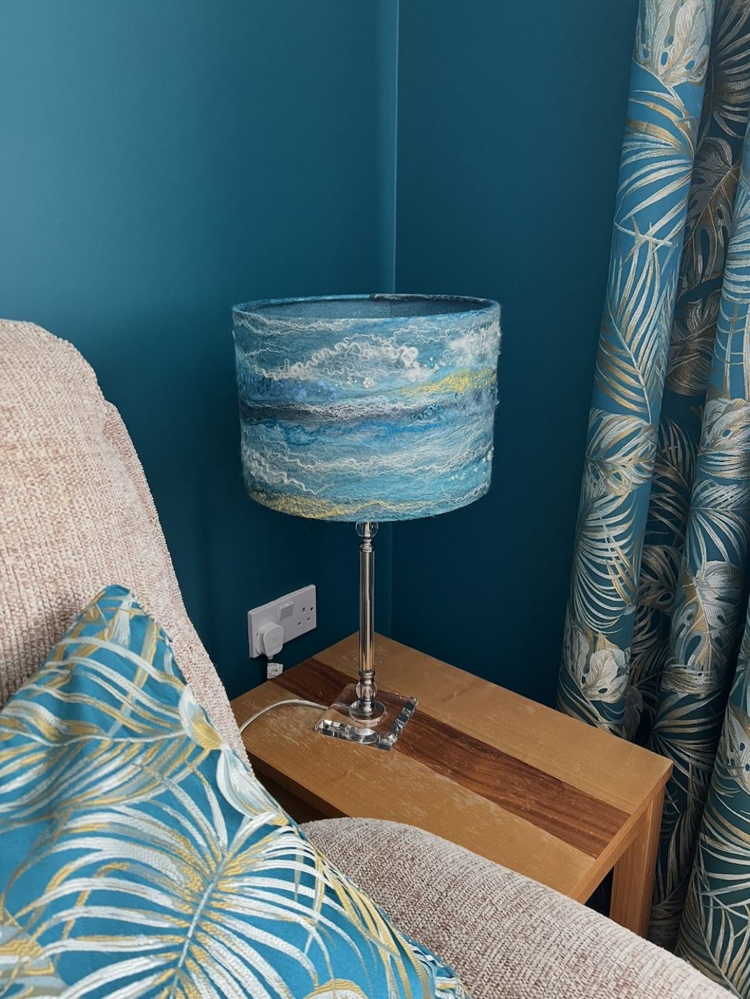 Teal felted silk and wool lampshade on a bedside lamp in a living room