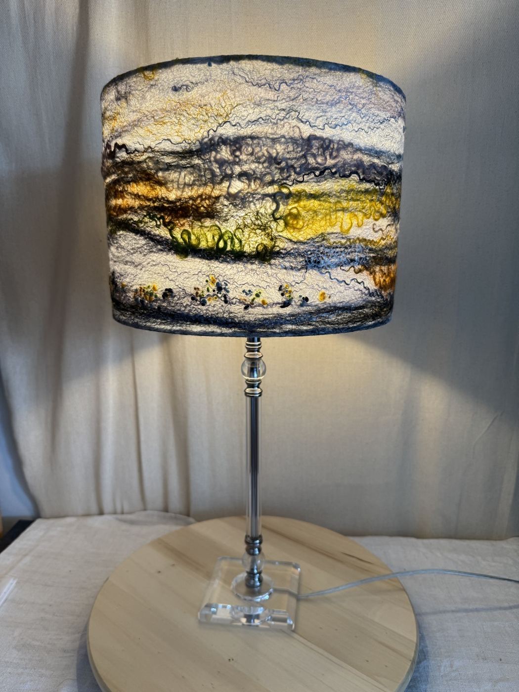 Felted landscape lampshade glowing warm yellow when switched on