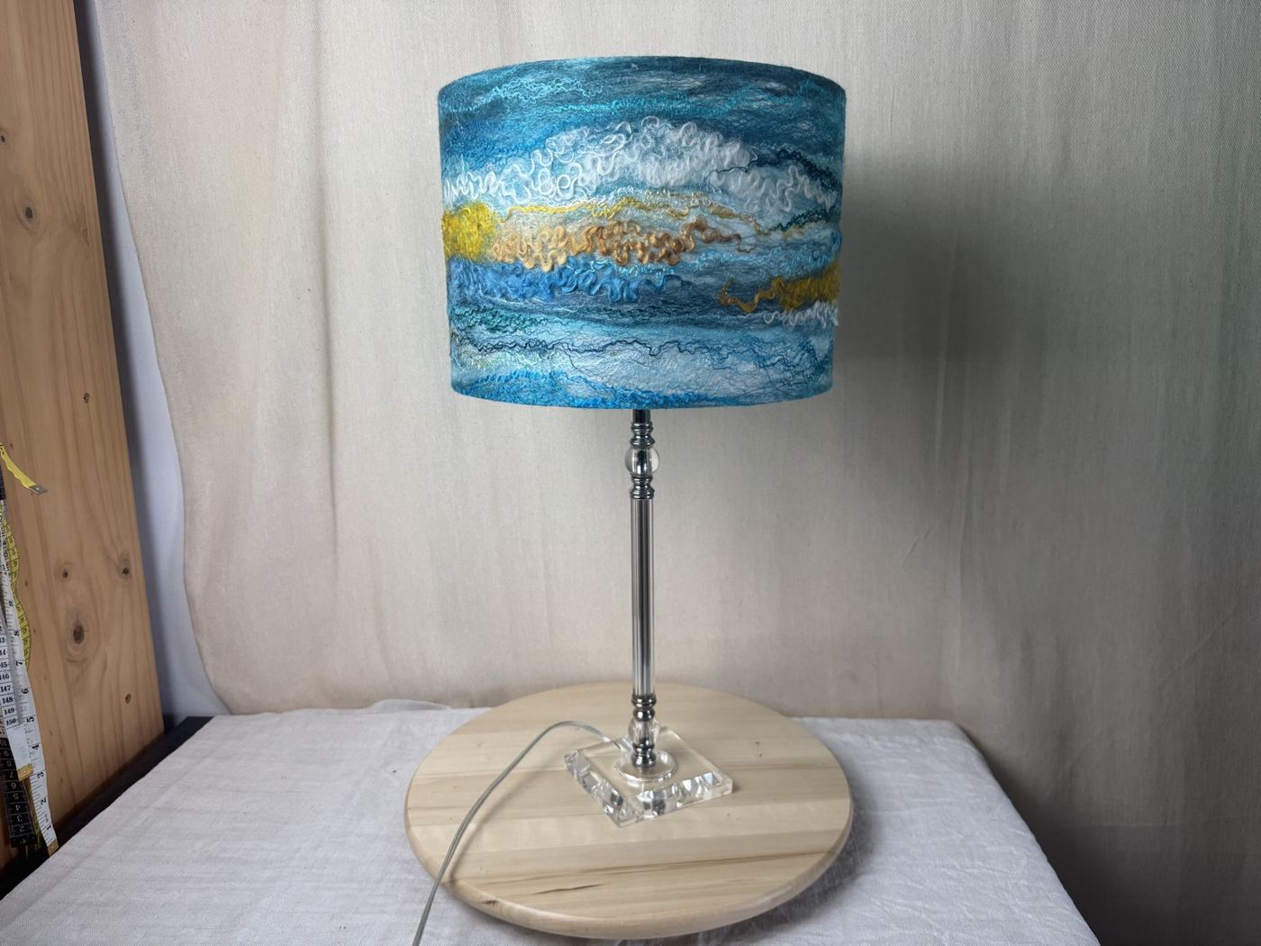 Teal, white and gold felted lampshade on a glass lamp base