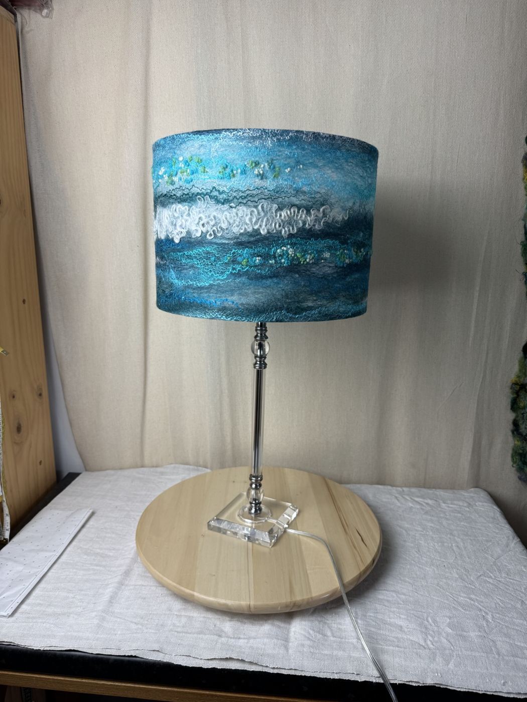 Teal and white sea-wave felted lampshade on a glass lamp base