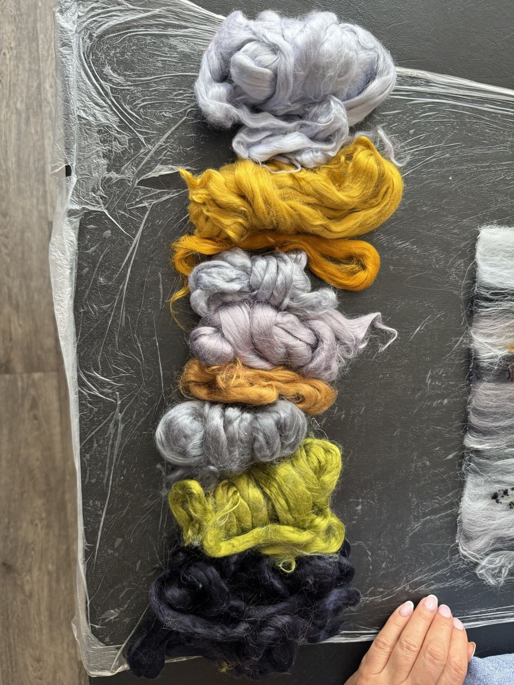 Gold, grey and lime wool fibres laid out for a design