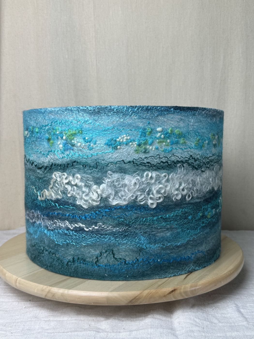 Close view of a teal silk and wool felted drum lampshade