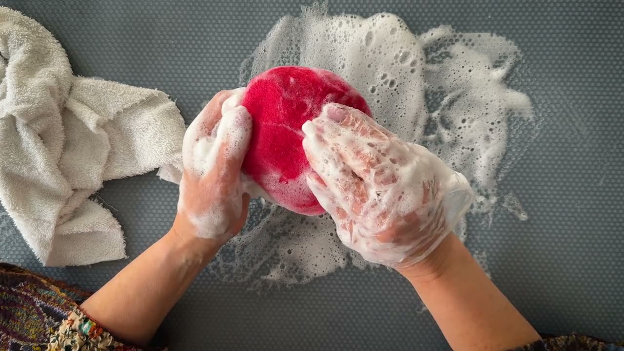 Hands shaping a soapy red felted cap