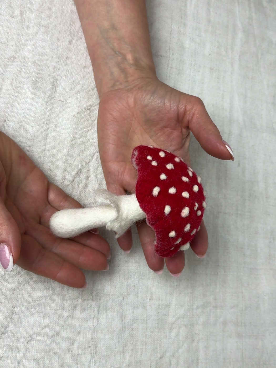 Felted fly agaric with a white stem resting in the hand